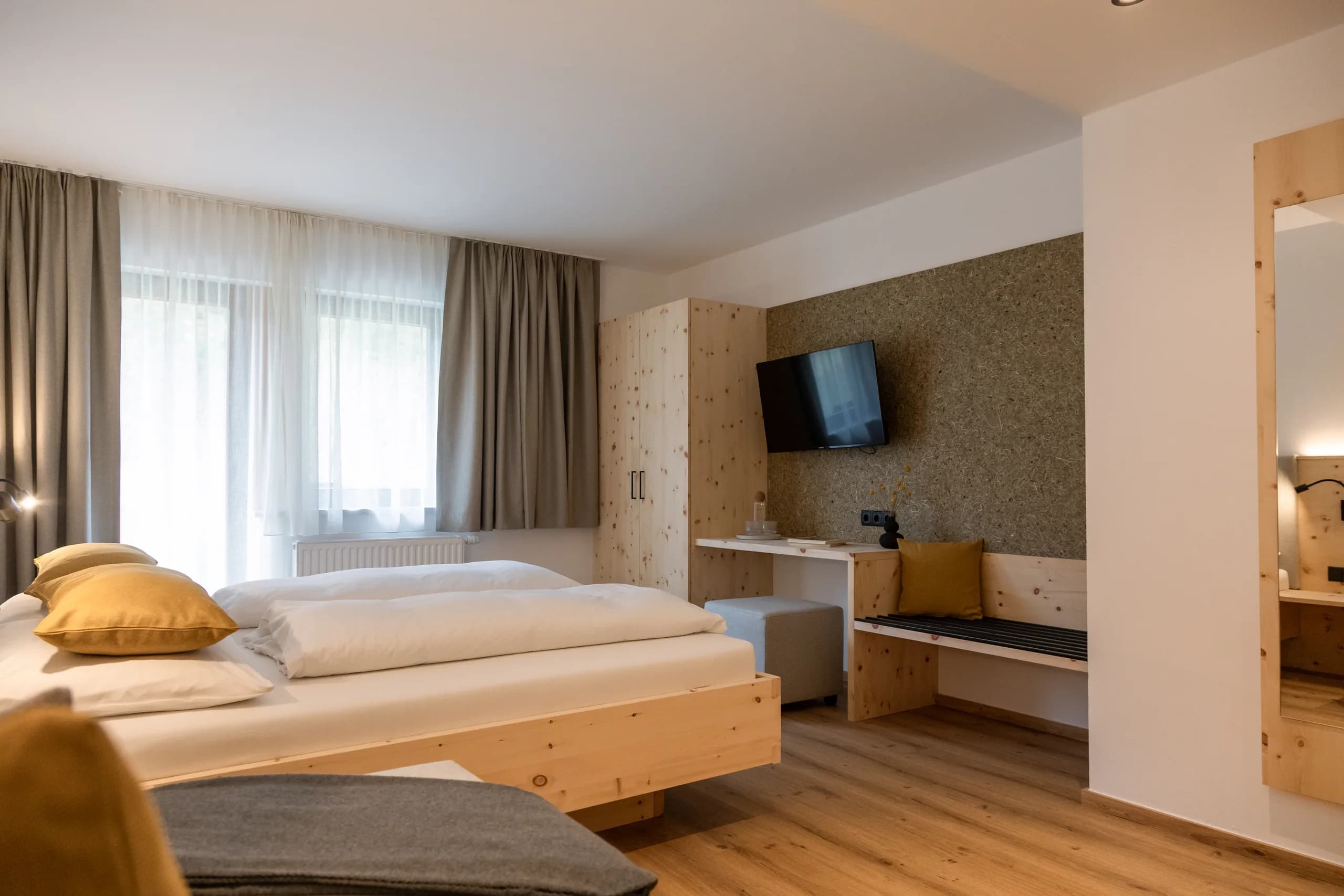 Zimmer Freiraum der Natur Residenz Anger Alm mit Bett, Fernseher und kleinem Schreibtisch