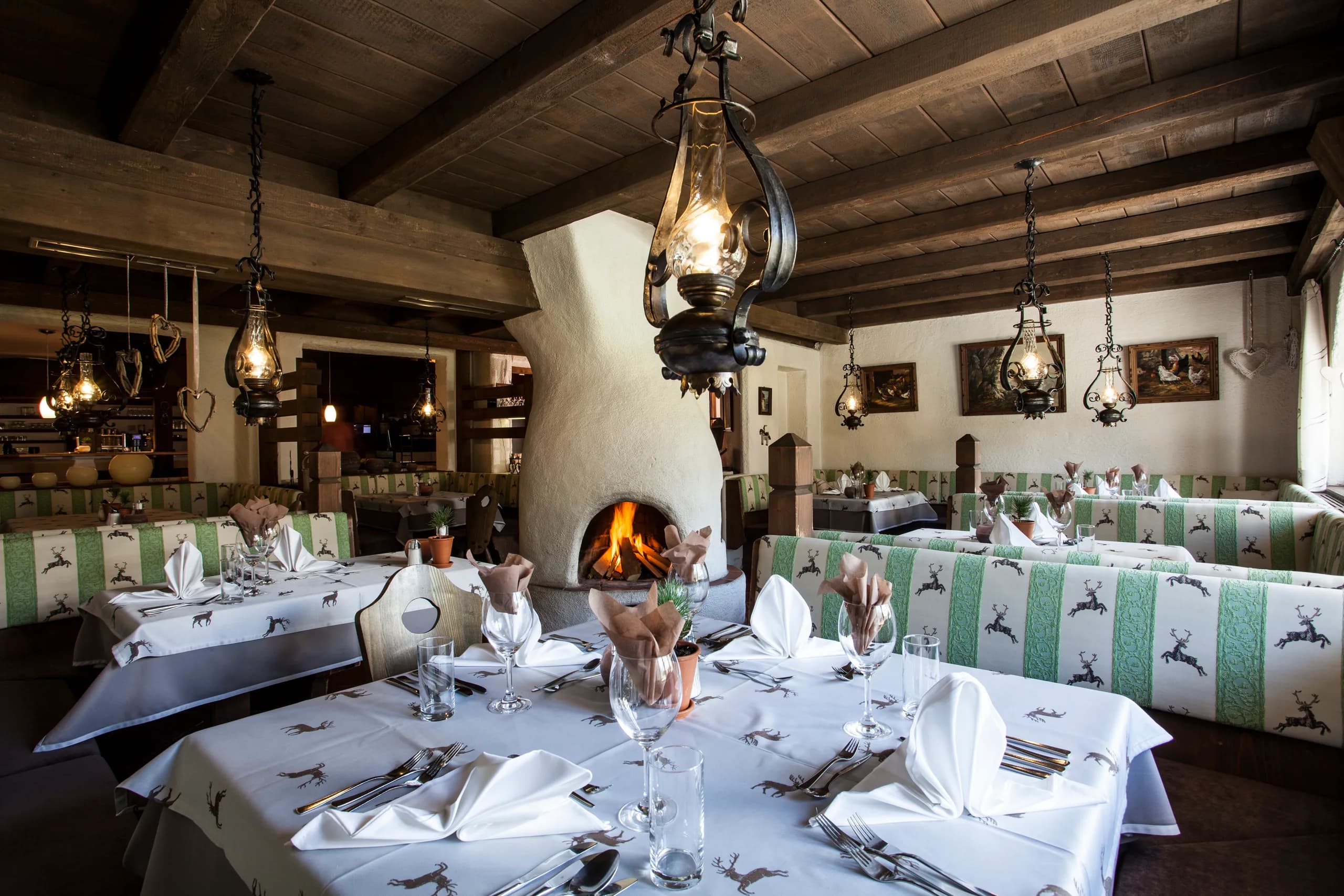 Festlich gedeckter Tisch vor einem knisternden Kamin im Restaurant der Natur Residenz Anger Alm