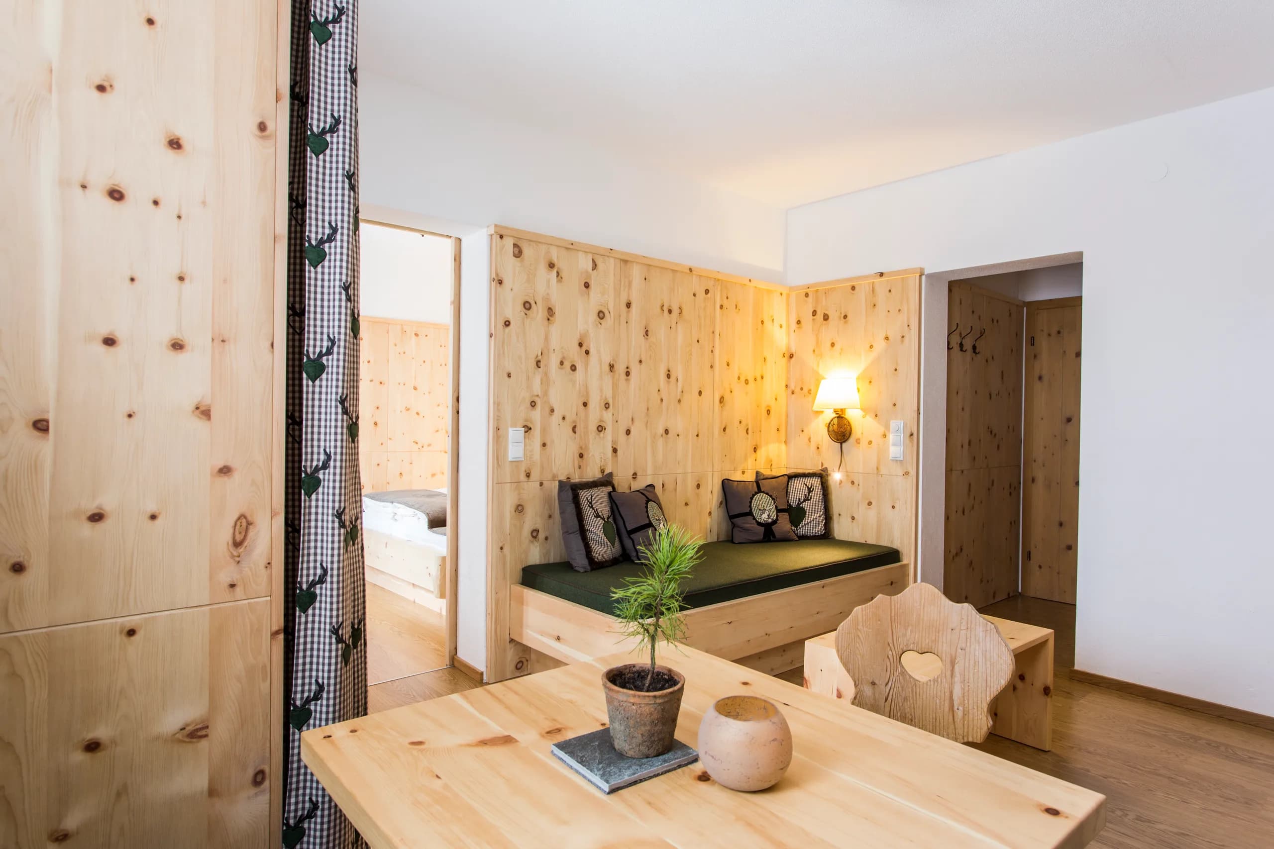 Wohn- und Essbereich mit Sitzbank und Blick zum Schlafbereich in der Zirben-Suite der Natur Residenz Anger Alm