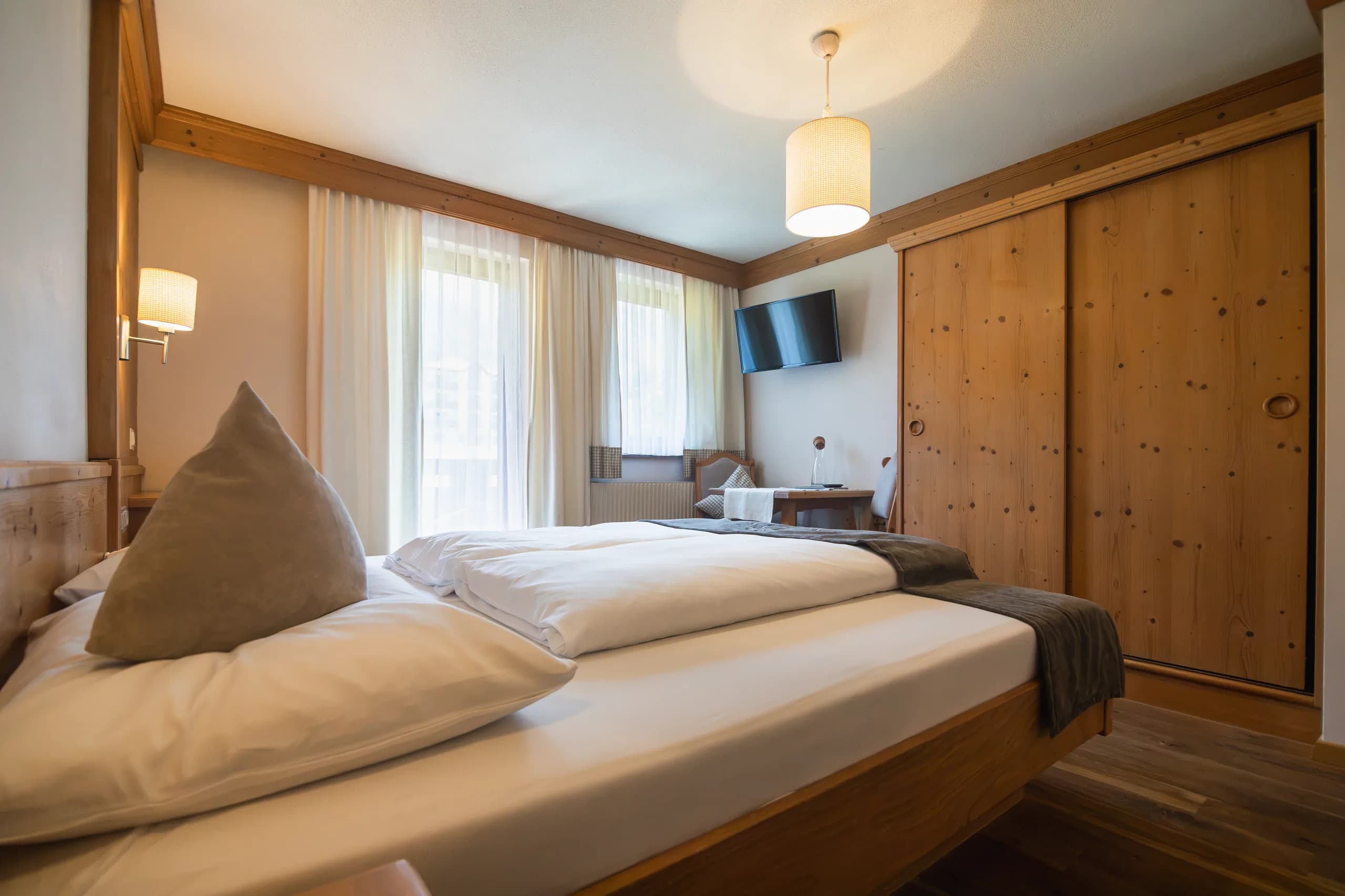 Blick über das Doppelbett zum Fenster des Natur-Raum-Zimmers