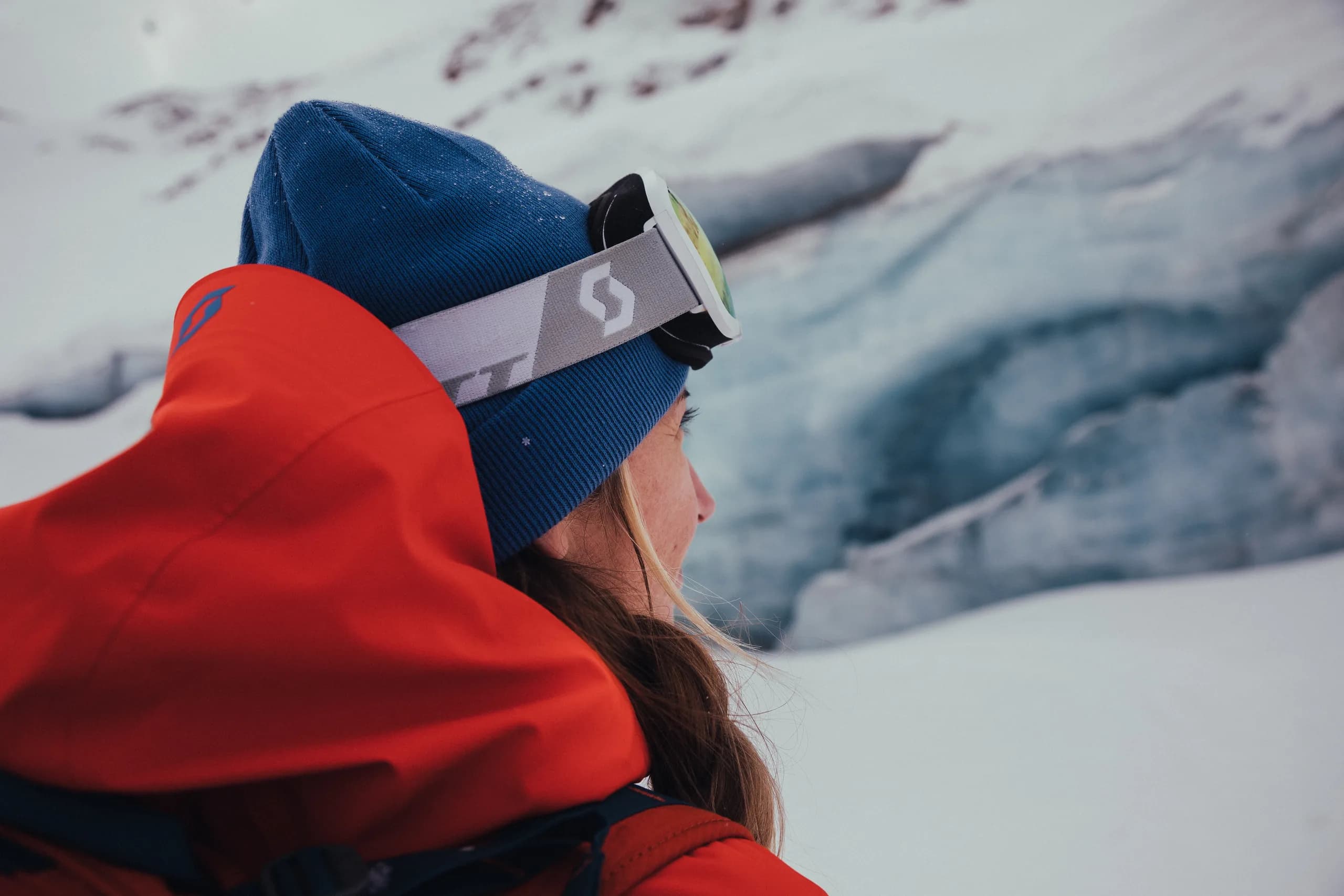 Skifahrer mit Helm und Skibrille vor einer Gletschereiswand