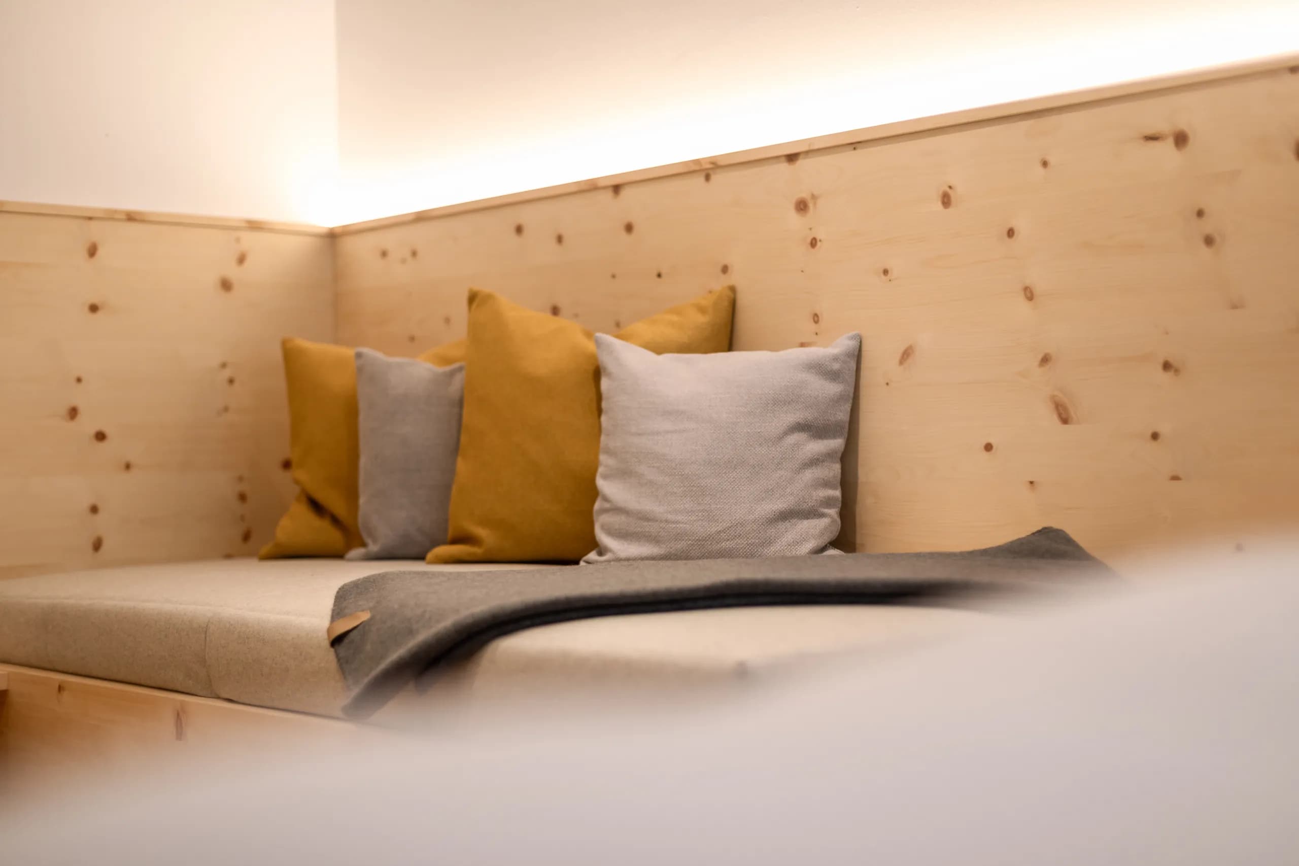 Kissen in Grau und Senfgelb vor Zirbenholzwand im Zimmer Freiraum der Natur Residenz Anger Alm