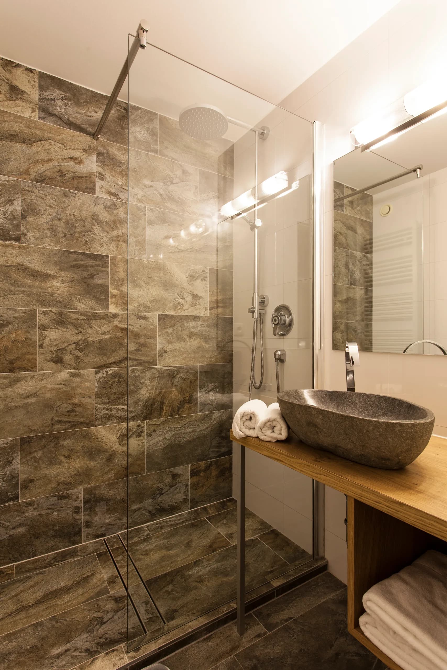 Badezimmer mit Naturstein-Waschbecken und Regendusche im Natur Raum DZ der Natur Residenz Anger Alm