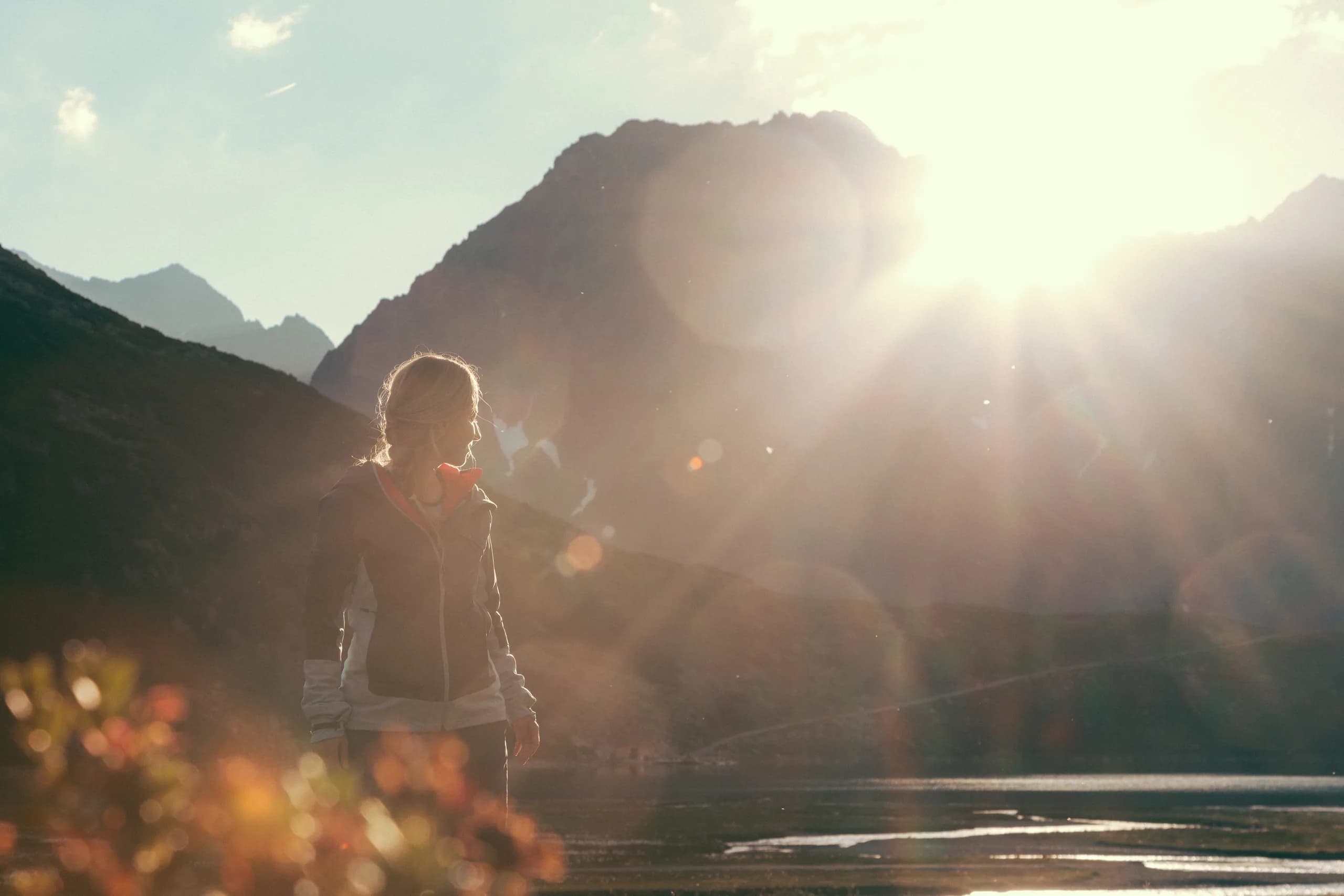 Wanderer erklimmt einen Felsen im Sonnenlicht mit Blick auf den Rifflsee nahe der Natur Residenz Anger Alm