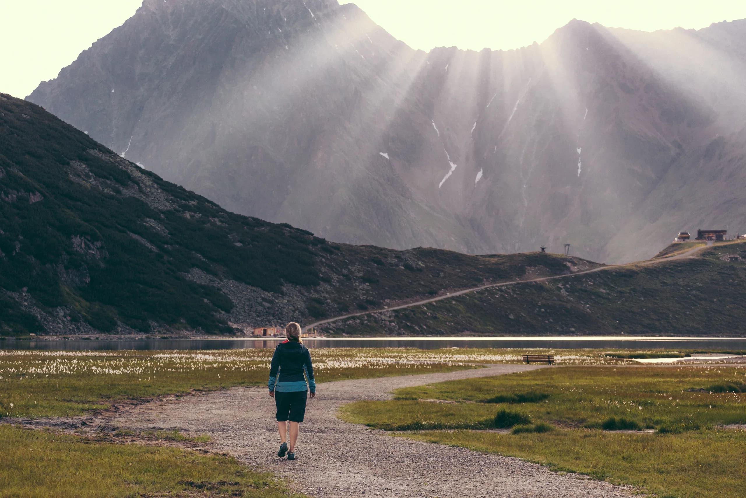 Wanderer auf steinigem Pfad mit dramatischem Lichtspiel über den Bergen nahe der Natur Residenz Anger Alm