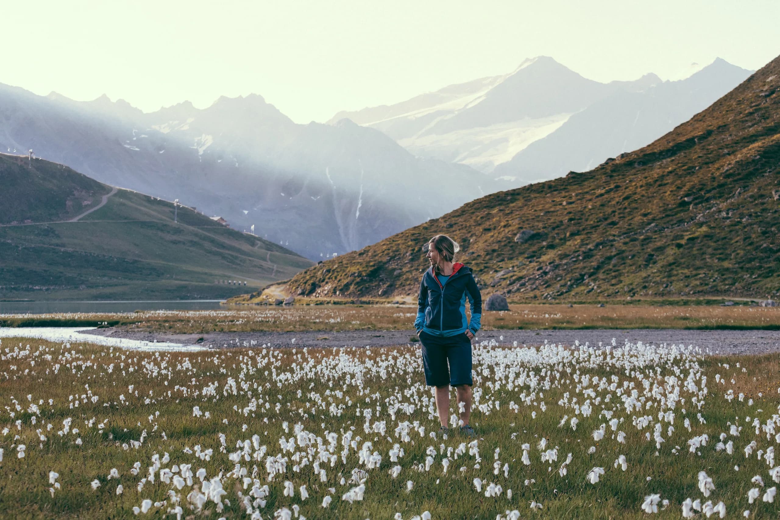 Wanderer in einer blühenden Wollgraswiese mit Bergpanorama nahe der Natur Residenz Anger Alm