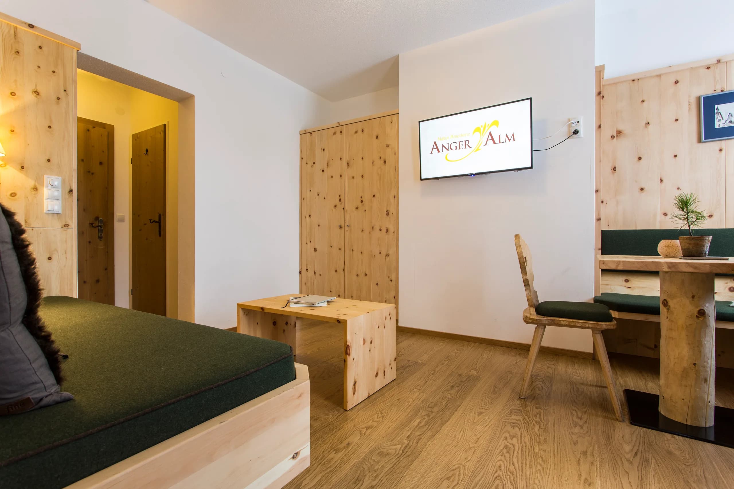 Sitzecke mit Zirbenholzschrank und Fernseher in der Zirben-Suite der Natur Residenz Anger Alm