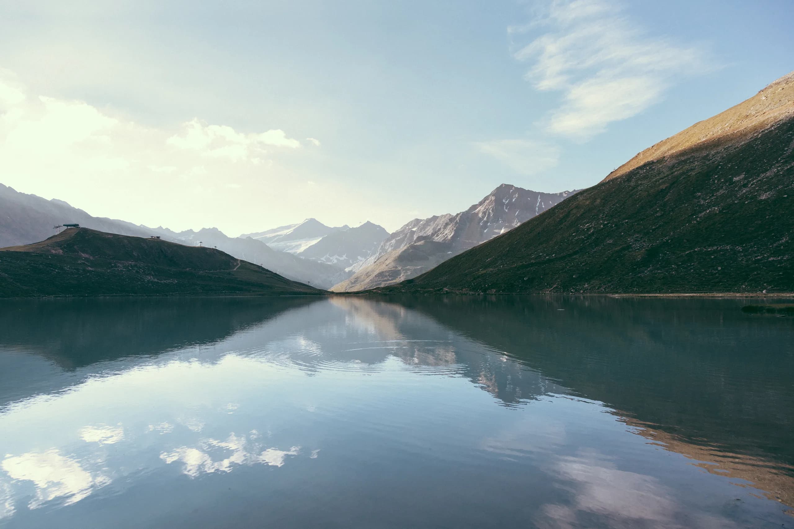Berggipfel und Wolken spiegeln sich im ruhigen Rifflsee