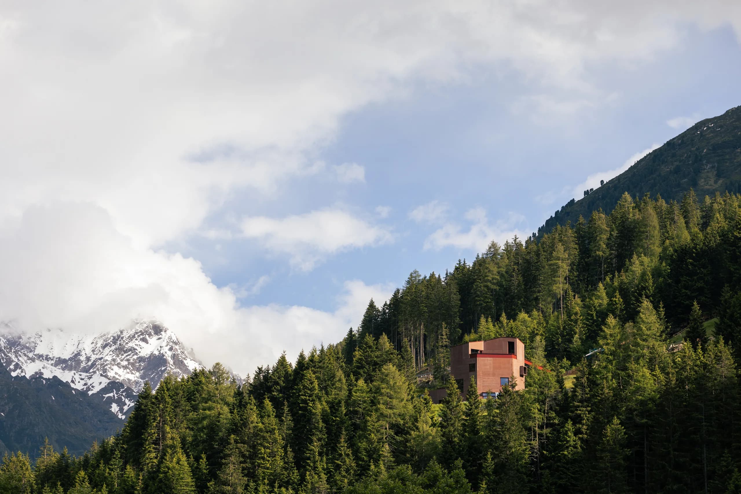 Roter Turm des Tiroler Steinbockzentrums vor Wald und Bergen